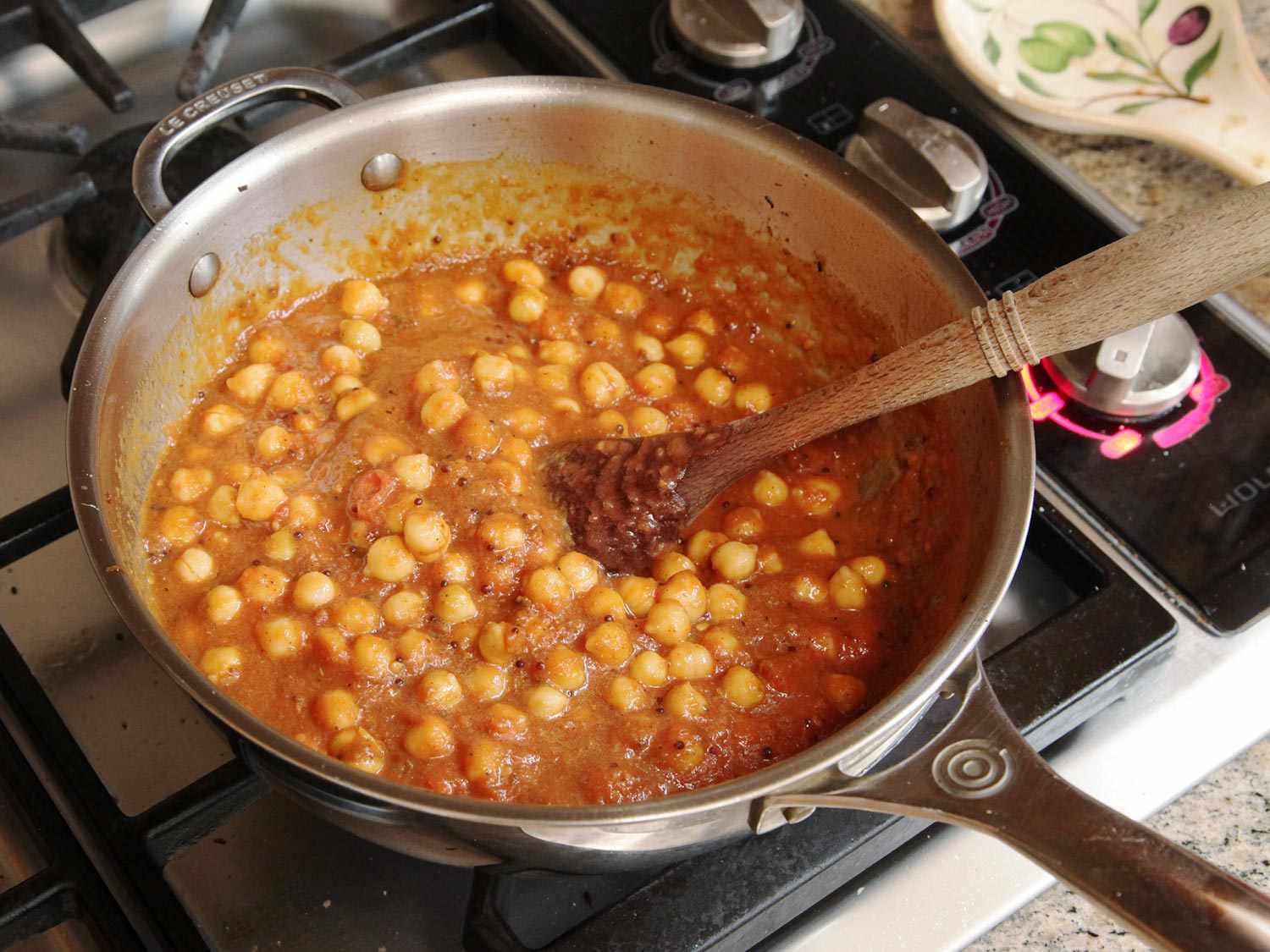 Tomatoes, chickpeas, and water are added to the pan.