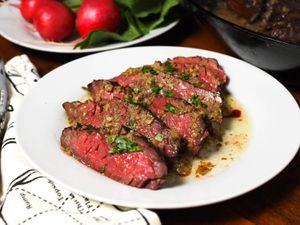 Slices medium-rare hanger steak with bagna cauda pan sauce on a plate
