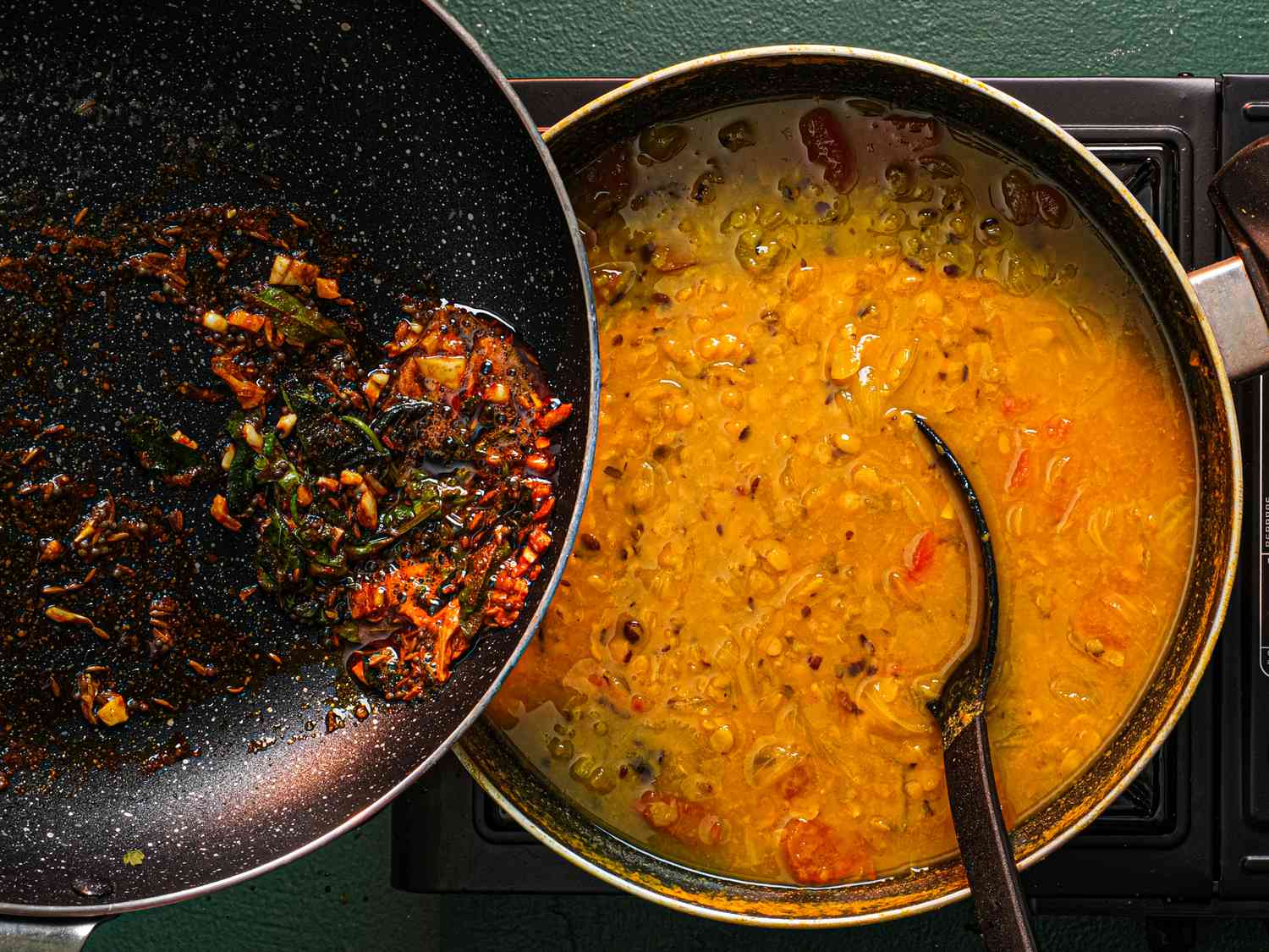 Pouring a ghee and spice mixture into toor dal.