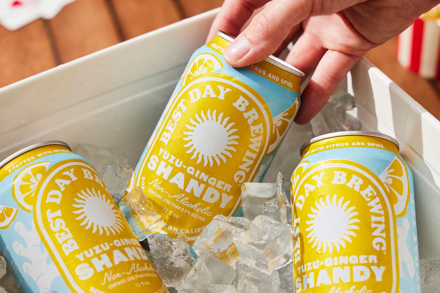 a hand grabbing a can of the best day yuzu ginger shandy out of an ice bucket