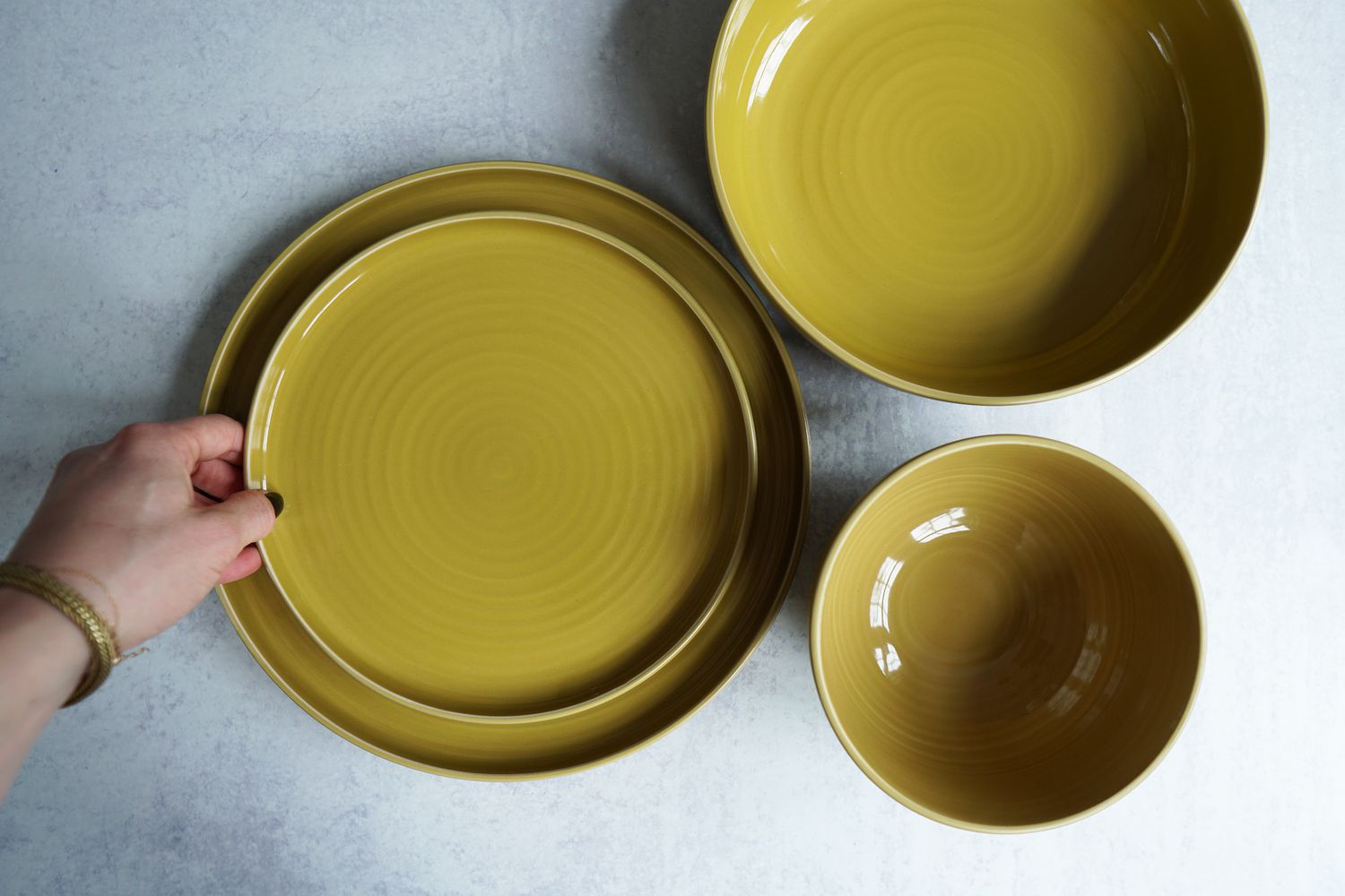 A hand placing a plate onto a larger plate