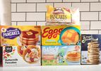 Five different brands of frozen pancakes displayed against a tile background including 365 Eggo and Buttermilk Pancakes packaging
