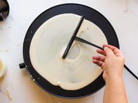 spreading crepe batter on the electric crepe pan