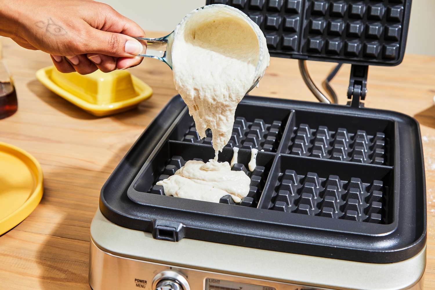 Waffle batter being poured into a waffle maker.
