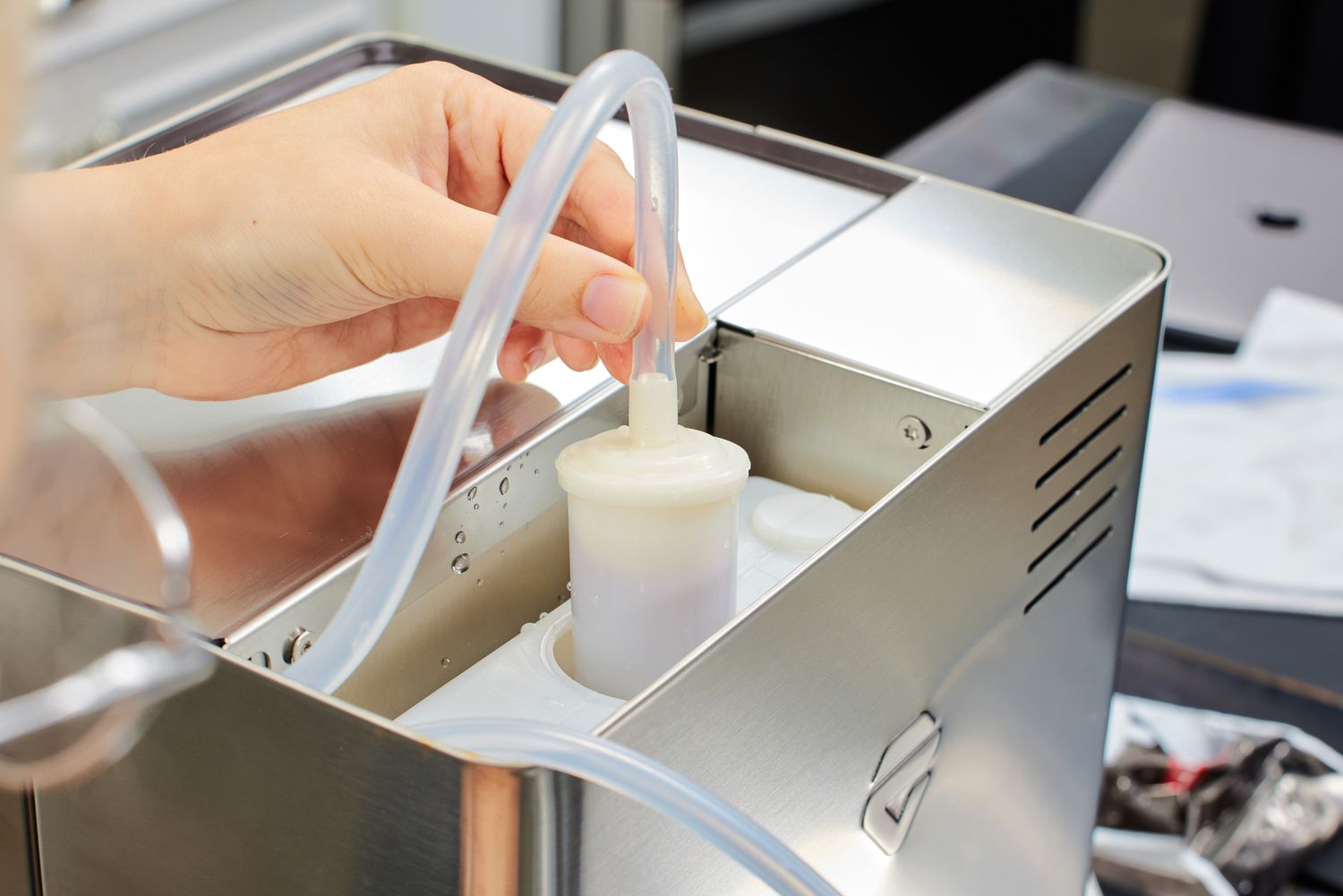 Closeup of a hand holding a tube attached to the Lelit Elizabeth Espresso Machine