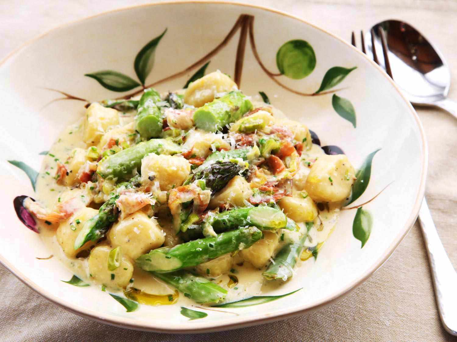 A bowl of homemade ricotta gnocchi with a creamy asparagus and prosciutto sauce.