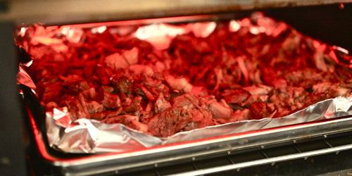 Broiling carnitas on a foil-lined rimmed baking sheet.