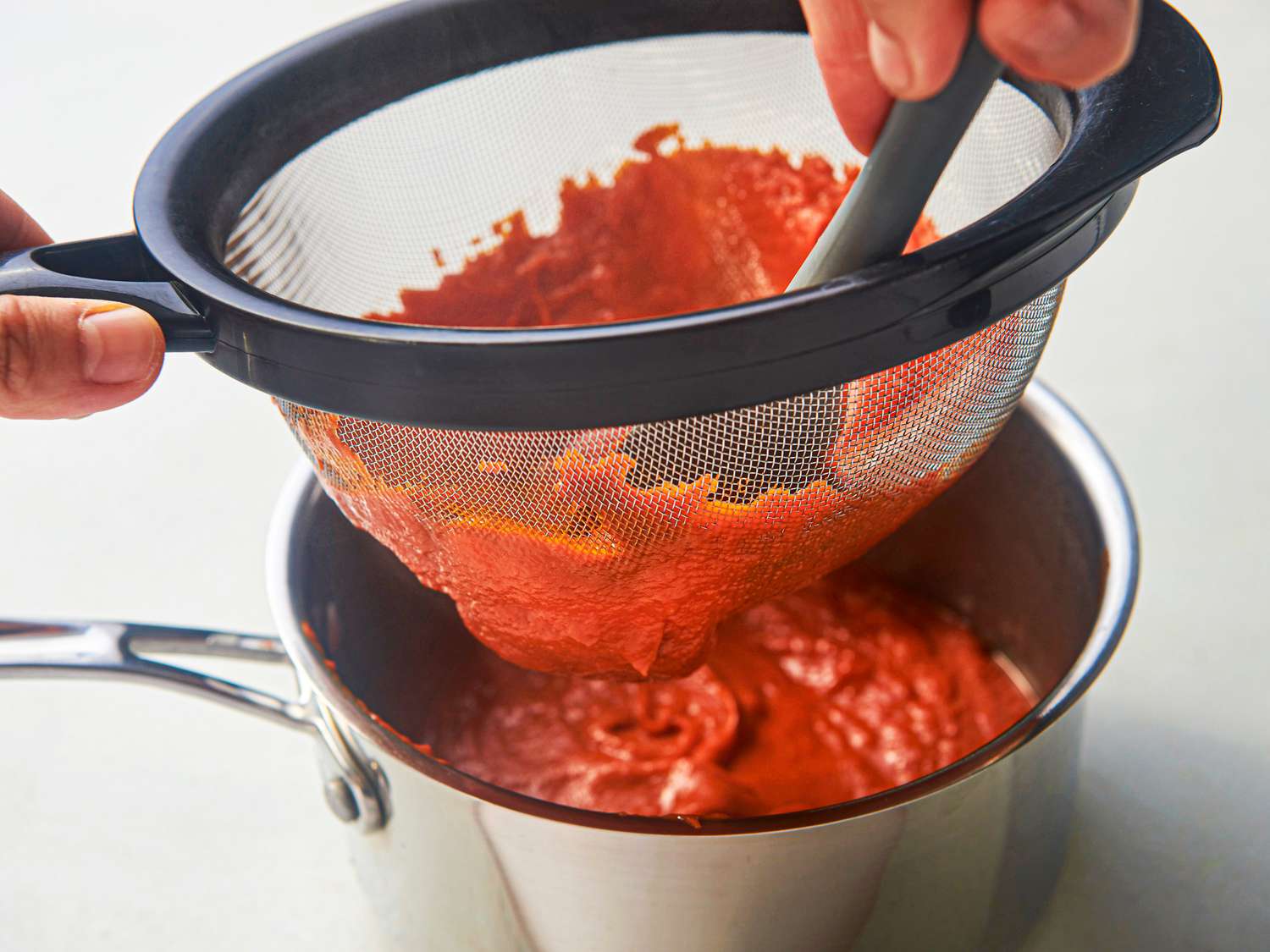 Side view of pushing ketchup through a strainer
