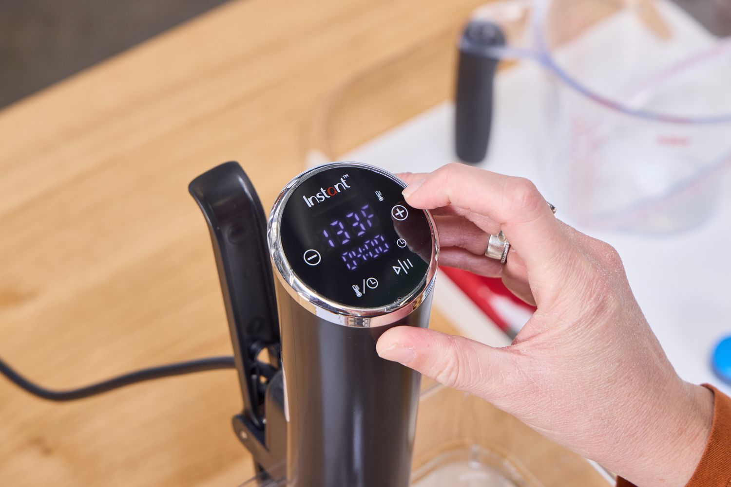 A person presses a button on the top of the Instant Accu Slim Sous Vide Immersion Circulator