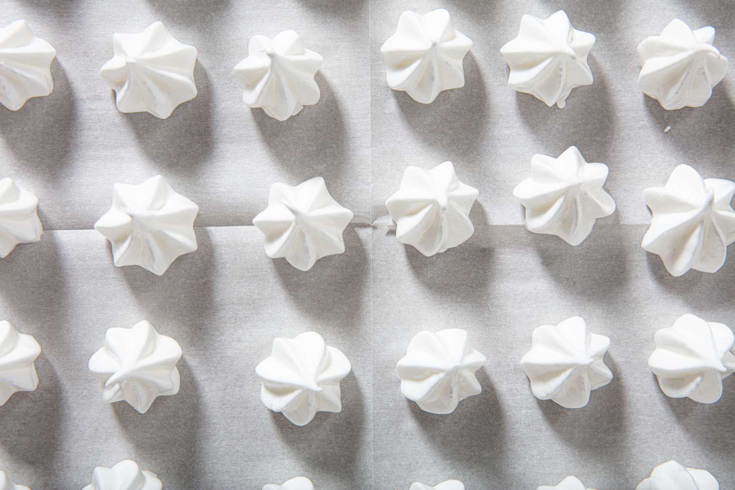 Piped meringues on a baking sheet.