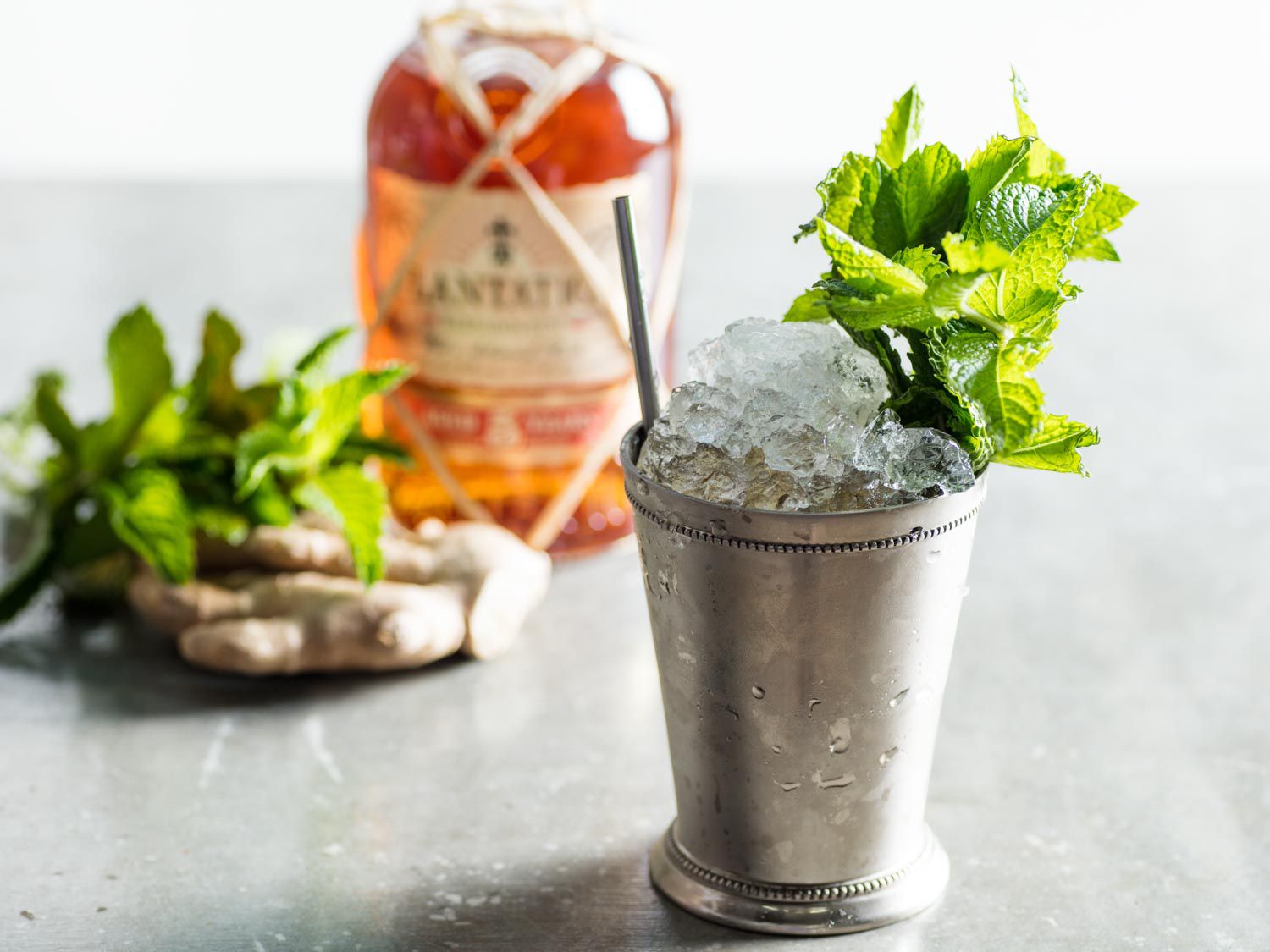 A dark and stormy julep cocktail, served in a silver julep cup, garnished with a large bouquet of mint sprigs.