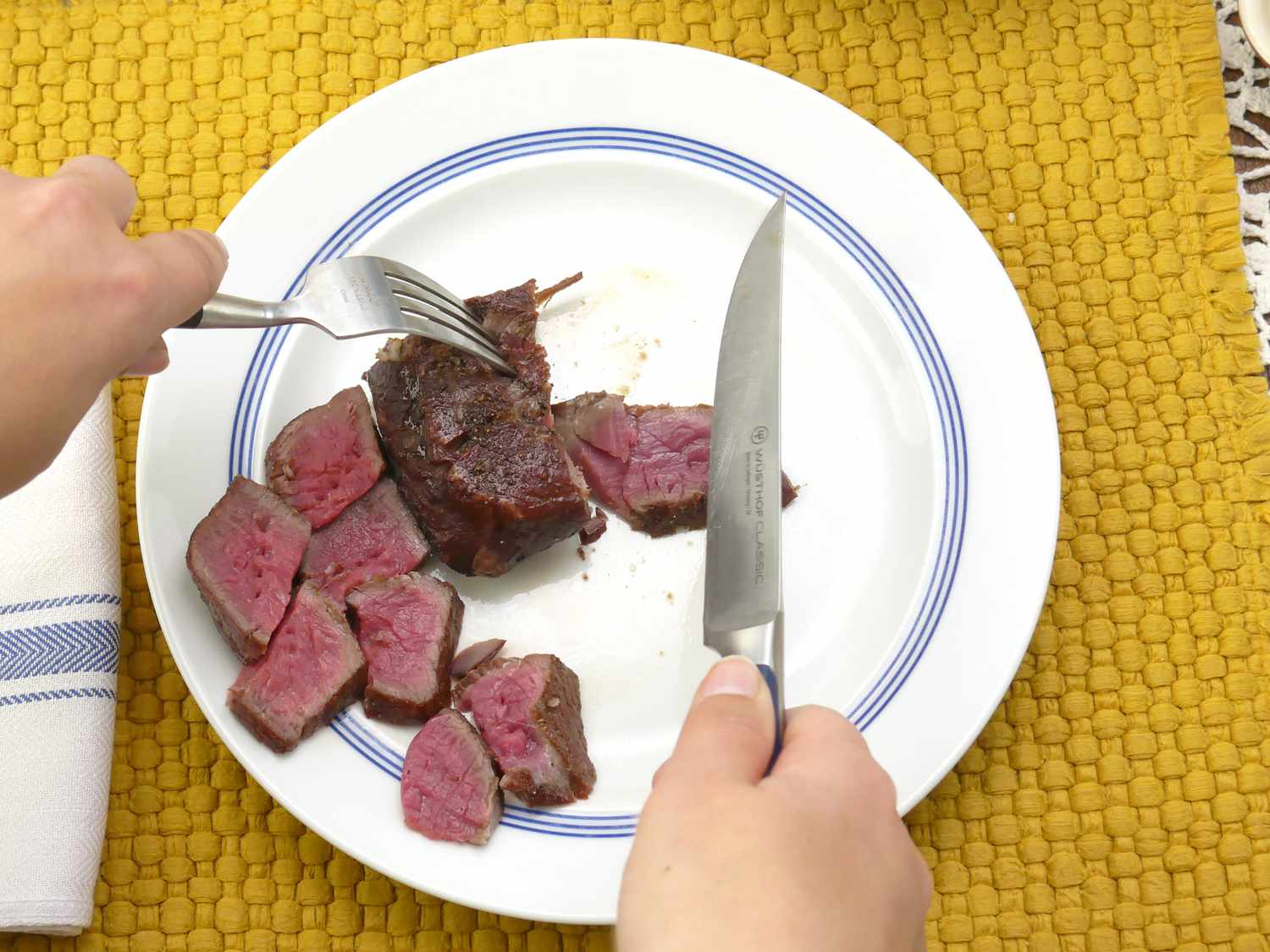 a person holding the wusthof steak knife over a sliced steak
