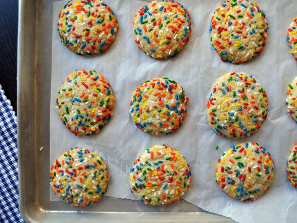 Line up of vanilla sprinkle cookies on a baking sheet. 