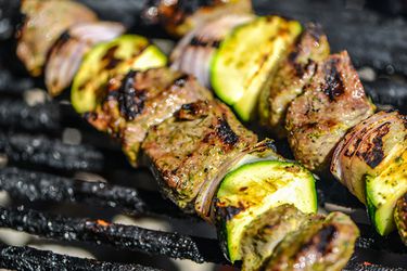Yogurt- and Mint-Marinated Lamb Skewers getting lightly charred in a grill grate.
