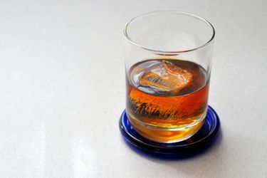 A Toronto cocktail in a high ball glass on a cobalt-blue coaster. 
