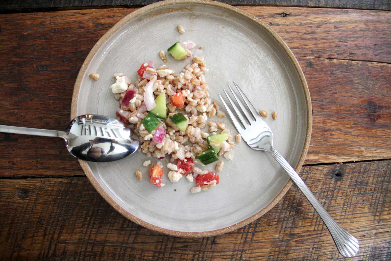 a spoon with a fork on a plate with farro salad