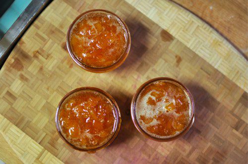 Overhead of three glass jars filled with homemade preserves.