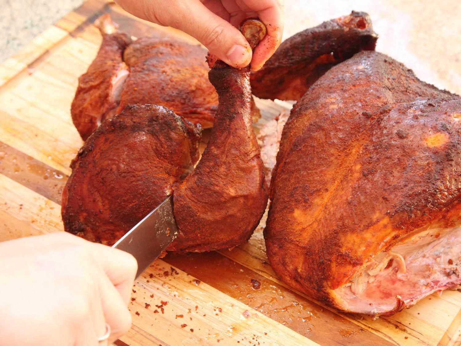 Splitting drumstick from thigh of a smoked turkey.
