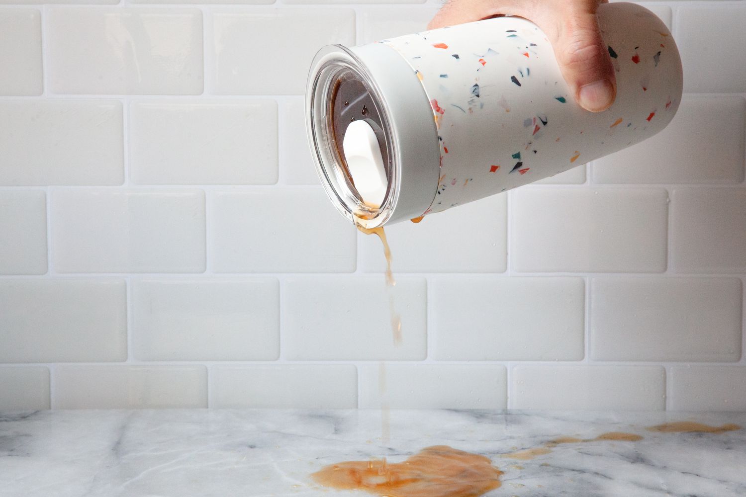 A person pours liquid out of a travel mug to demonstrate leakage.
