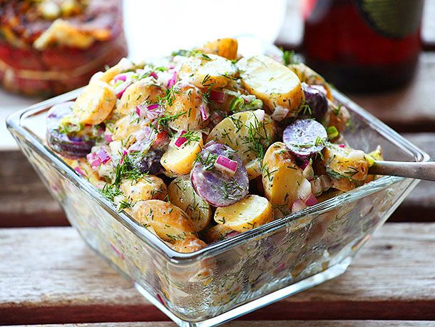 Close-up of the bowl of fingerling potato salad, studded with red onion and showered with fresh chopped dill.