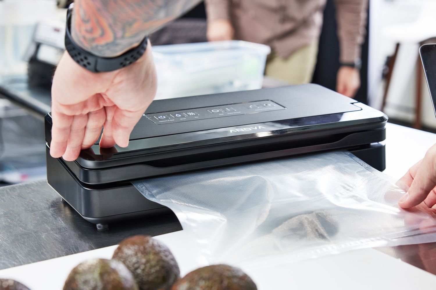 A person using a vacuum sealer to vacuum seal an avocado half
