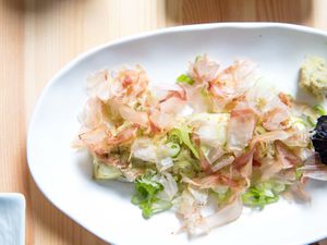 A white plate with Japanese-style broiled eggplant and shaved bonito flakes. 