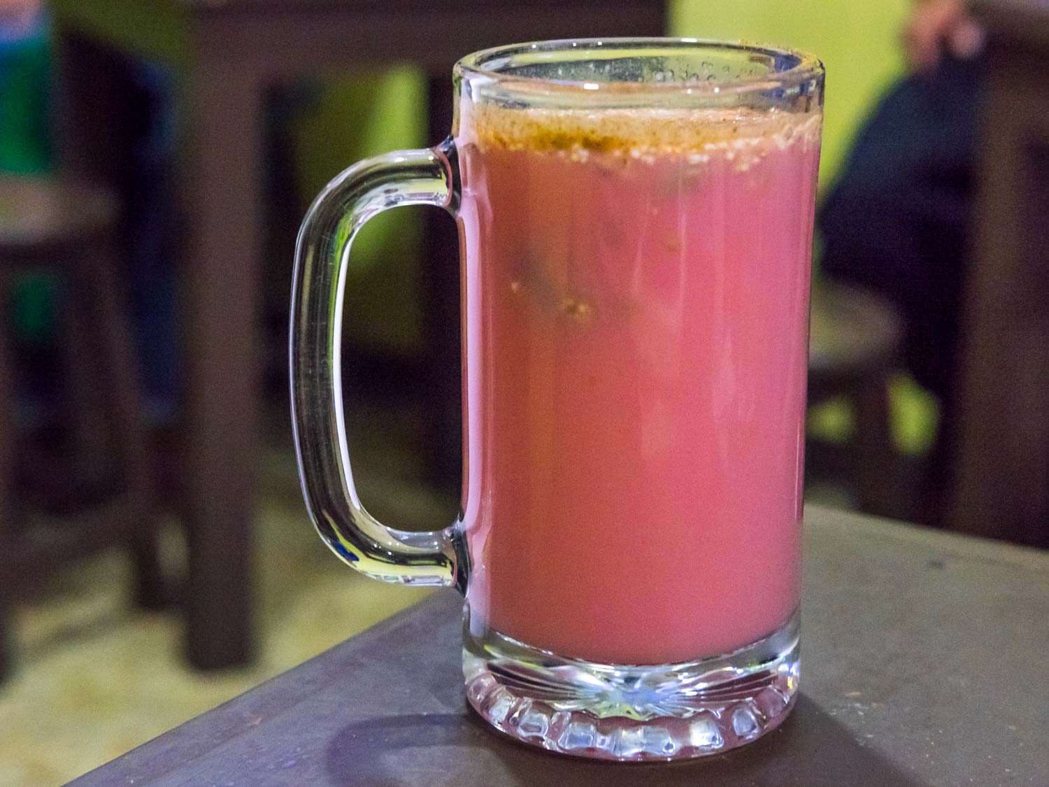 A large glass full of pink-hued pulque curado.