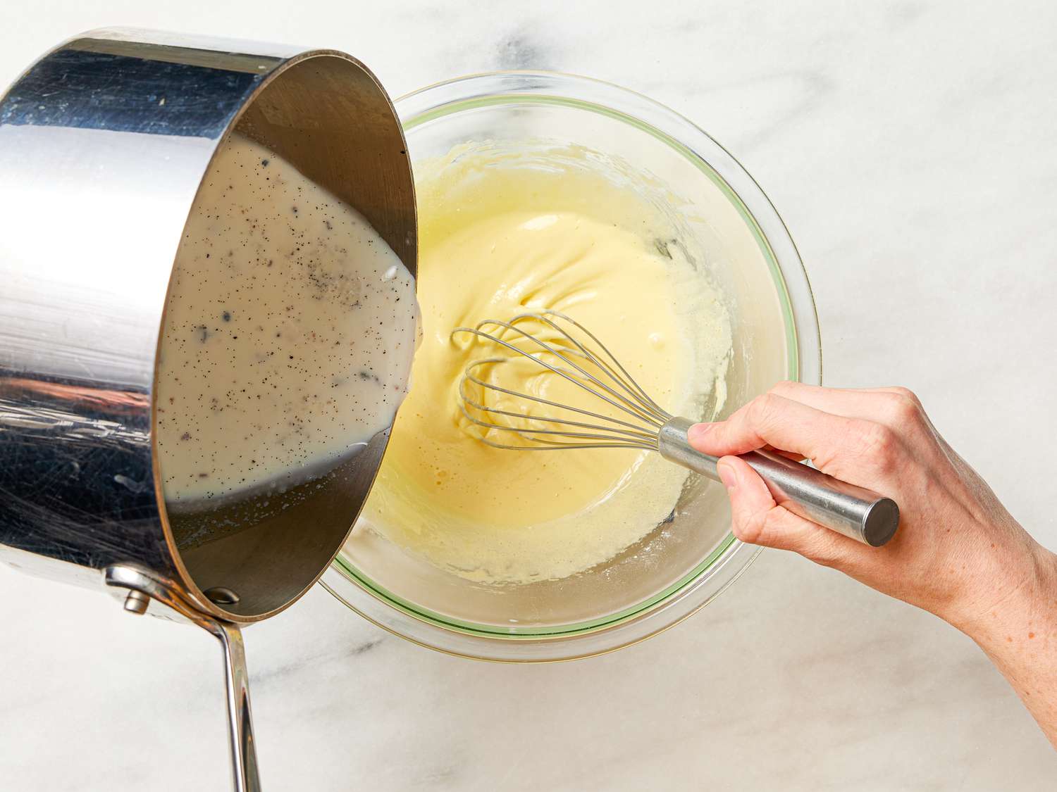 Pouring vanilla mixture while whisking eggs