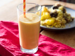 Mango lassi in a tall glass with a straw