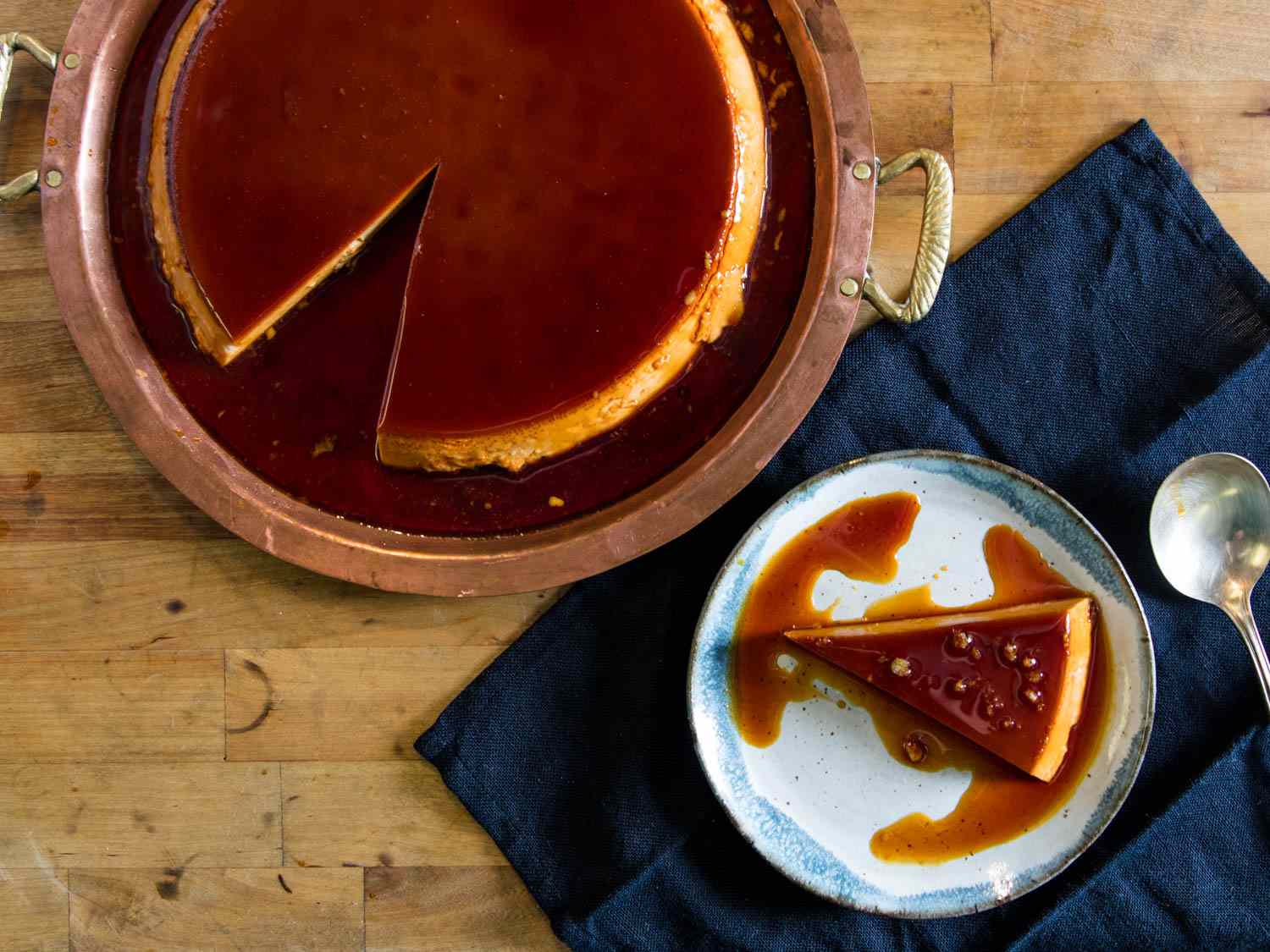 Overhead view of a double-caramel flan with a slice on a plate