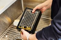 A person emptying out the liquid from the drip tray of the Gaggia Classic Pro Espresso Machine
