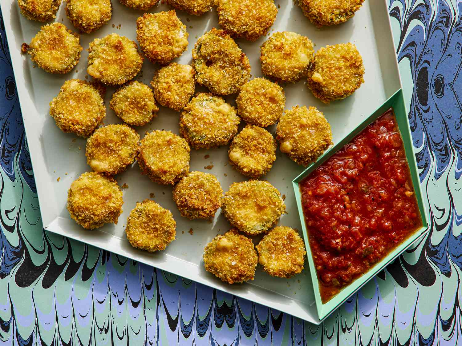Finished jalapeno poppers on a plastic tray with a funky background and red dipping sauce