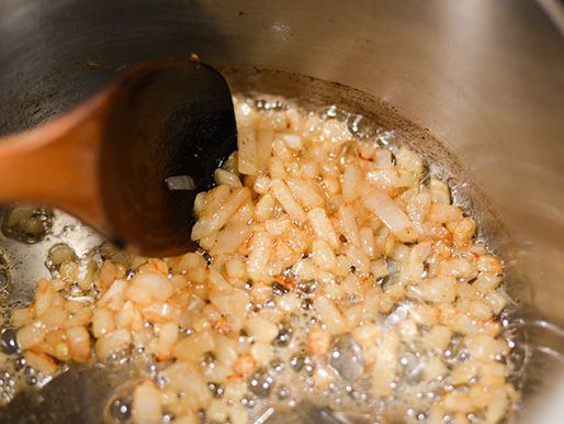 Diced onion is sautéed in a pot.
