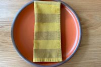 Yellow stripe cloth napkin on top of a orange plate