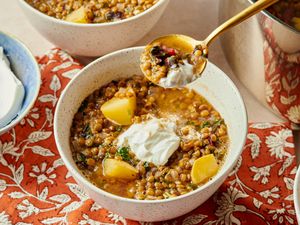 Lebanese brown lentil soup in a bowl with a dollop of yogurt served with pieces of potato and lentils visible
