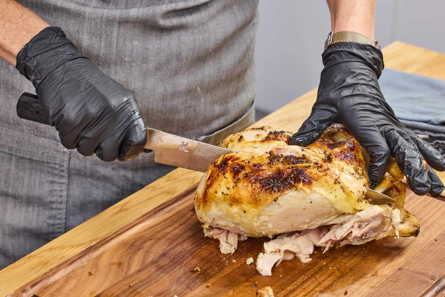 A person slices a chicken with the Miyabi Koh 9.5 Inch Slicing Knife