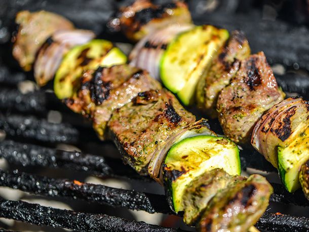 Yogurt- and Mint-Marinated Lamb Skewers getting lightly charred in a grill grate.