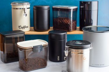 Numerous coffee canisters holding coffee on a kitchen countertop.