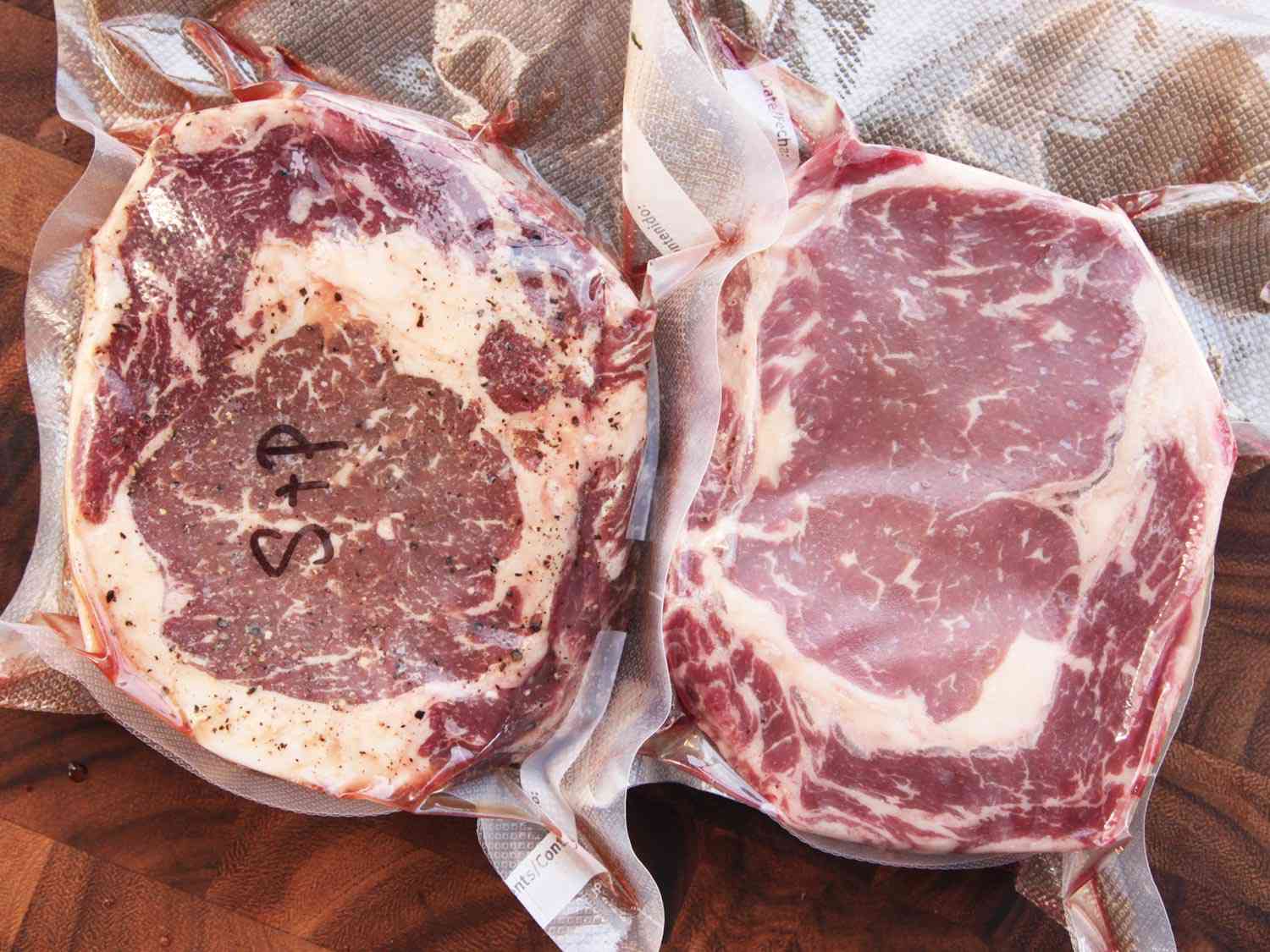 Two raw steaks vacuum sealed in sous vide bags, the one on the left side has been seasoned with salt and pepper.