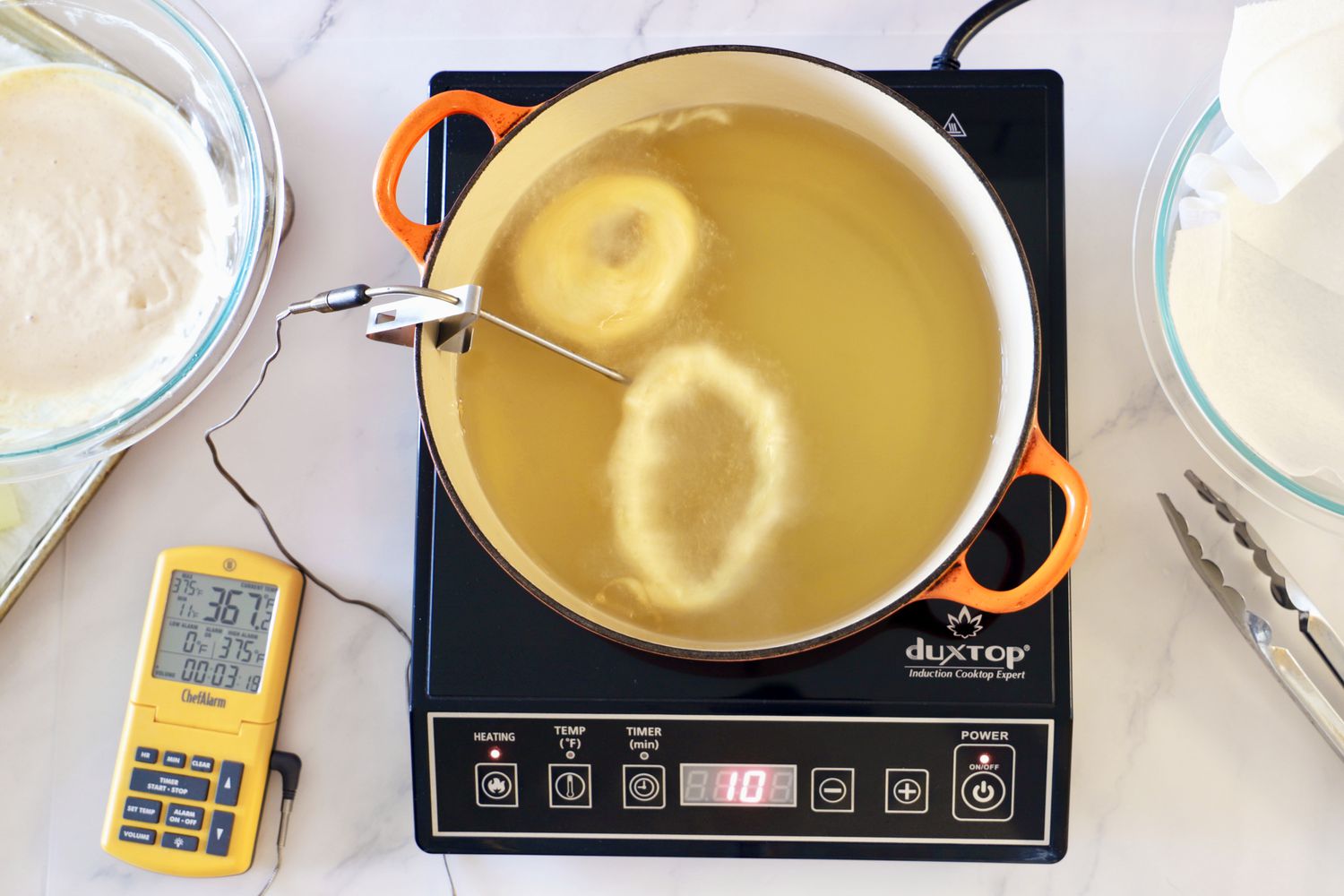 Donuts being fried in a Dutch oven set on an induction burner.