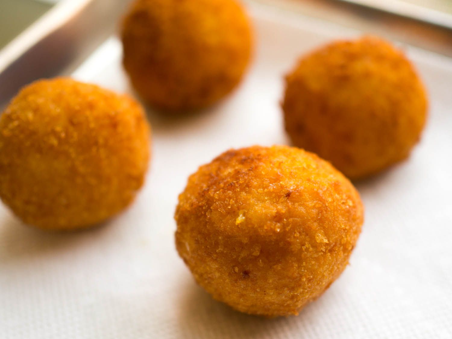 Close-up of arancini draining on a paper towel-lined baking sheet.