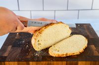 Person slicing bread with Tojiro F-737 Bread Slicer