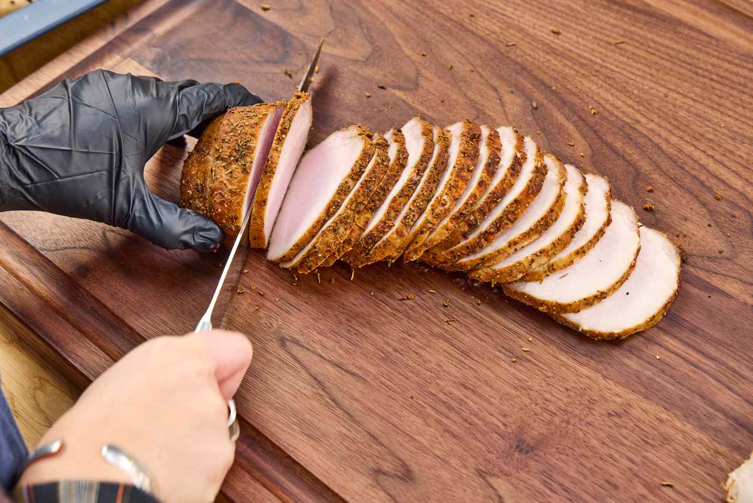 A person slices meat with the Wüsthof Classic 9 Inch Hollow Edge Carving Knife