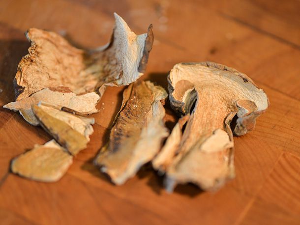 Dried porcini mushrooms on a wooden cutting board.