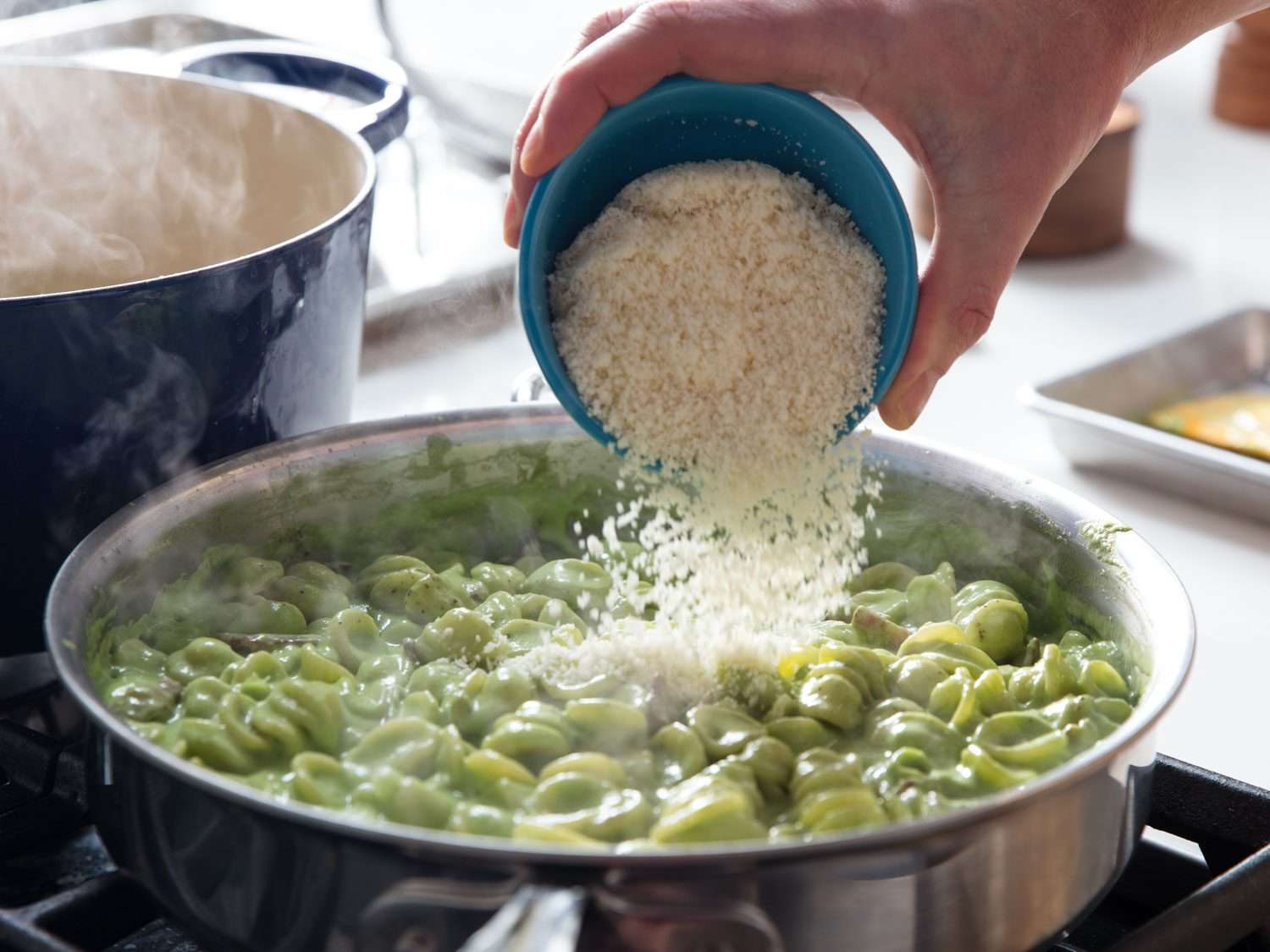 Adding Parmigiano cheese to the pasta.