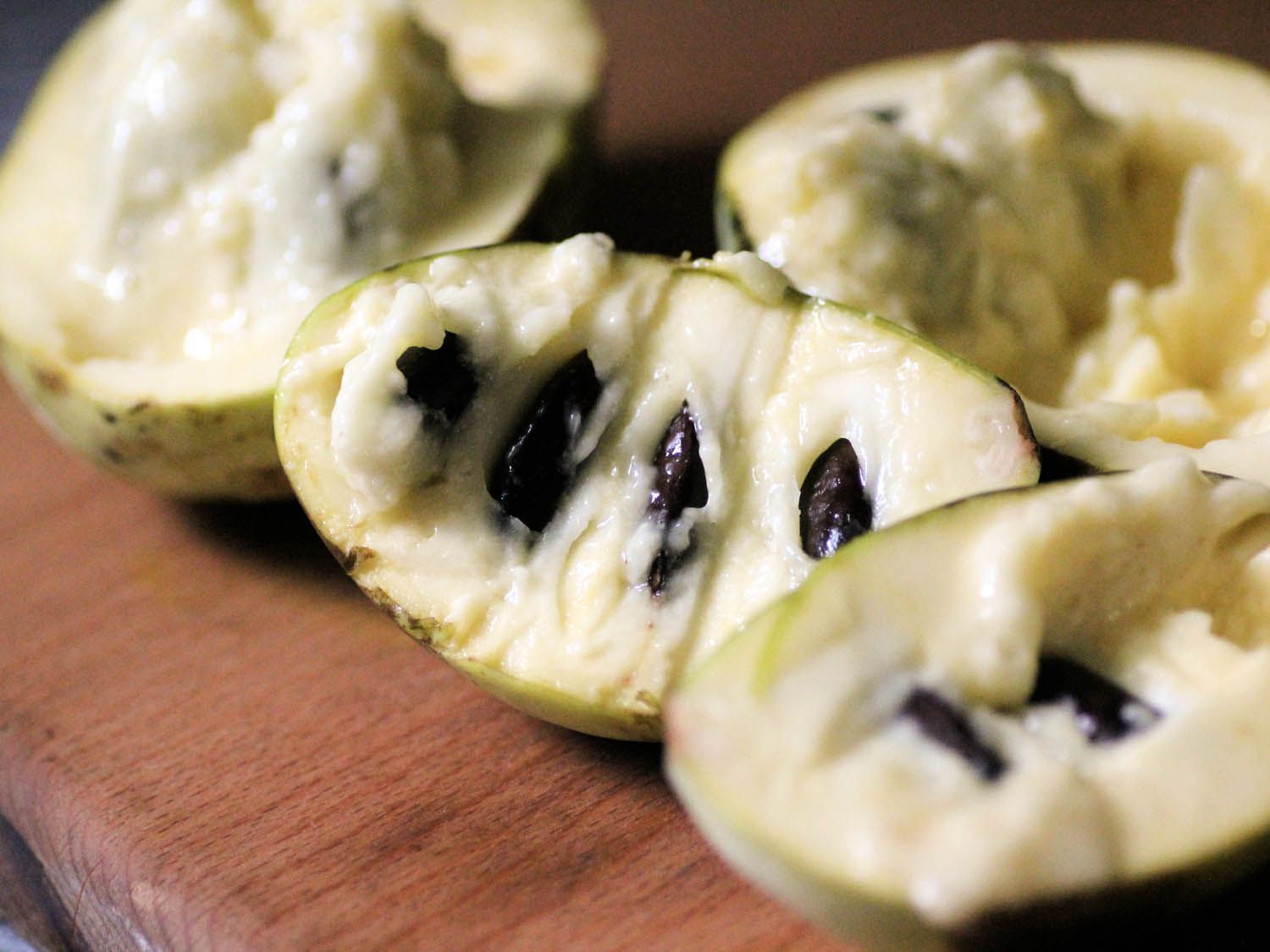 Four pawpaw halves resting on a cutting board