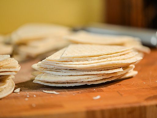Closeup of stacks of quartered corn tortillas on a cutting board.