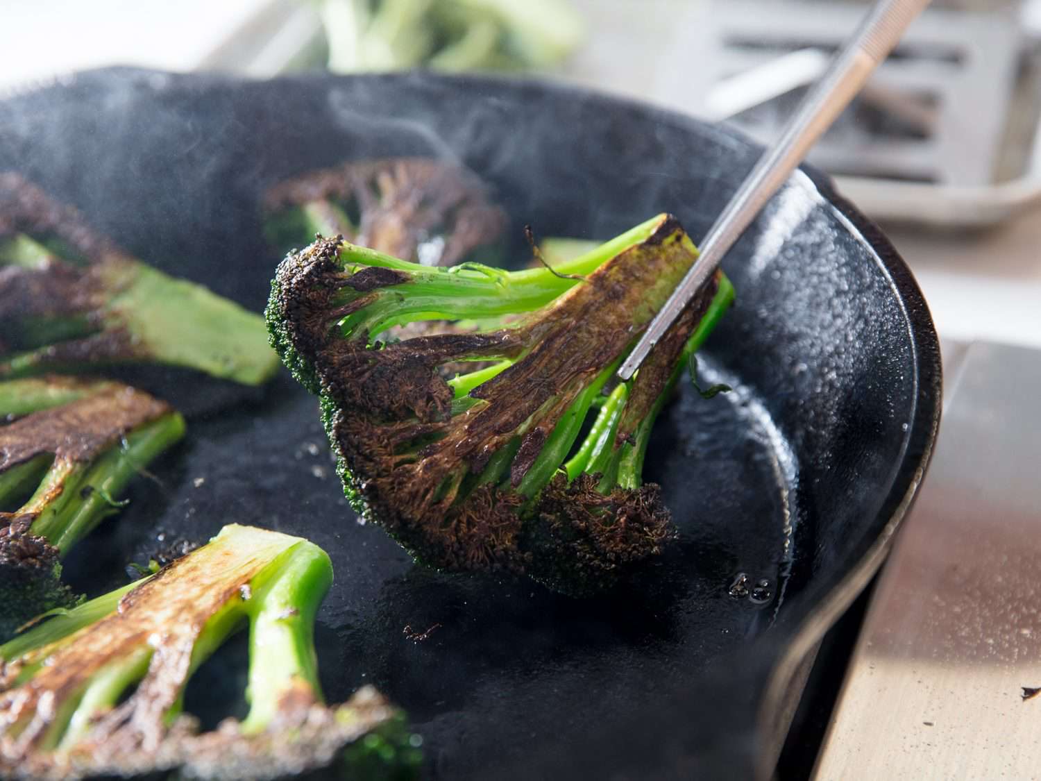 Closeup of turning broccoli pieces after charring on first side.