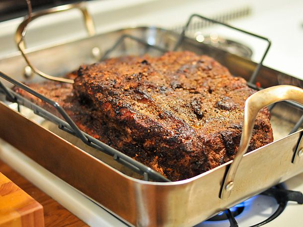 A smoked brisket transfered to a baking dish and cooking on a stovetop 