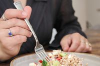 A person using a fork from the Lenox Portola 65-Piece Flatware Set 